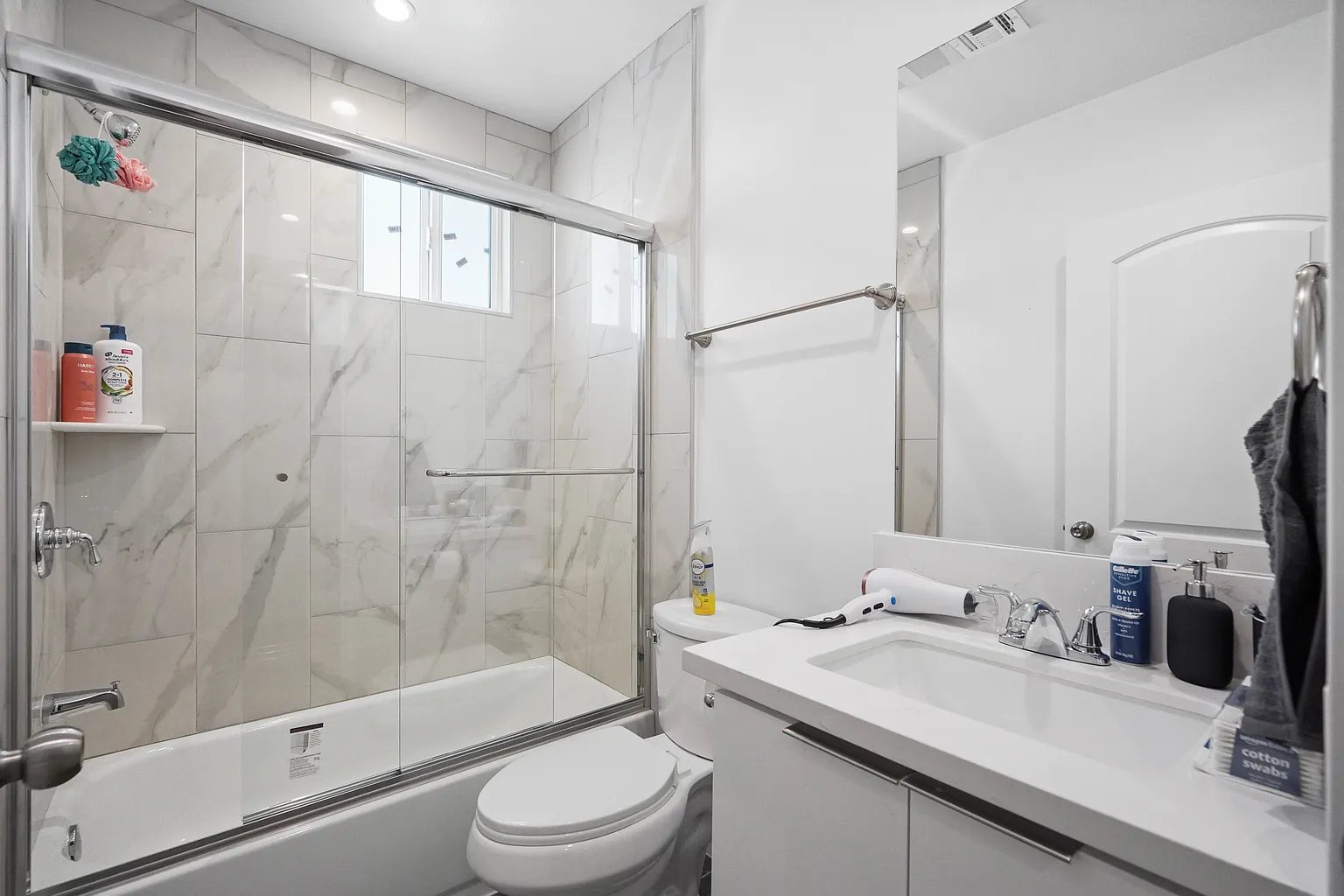 Culver City furnished apartment modern bathroom with marble tile shower and white vanity