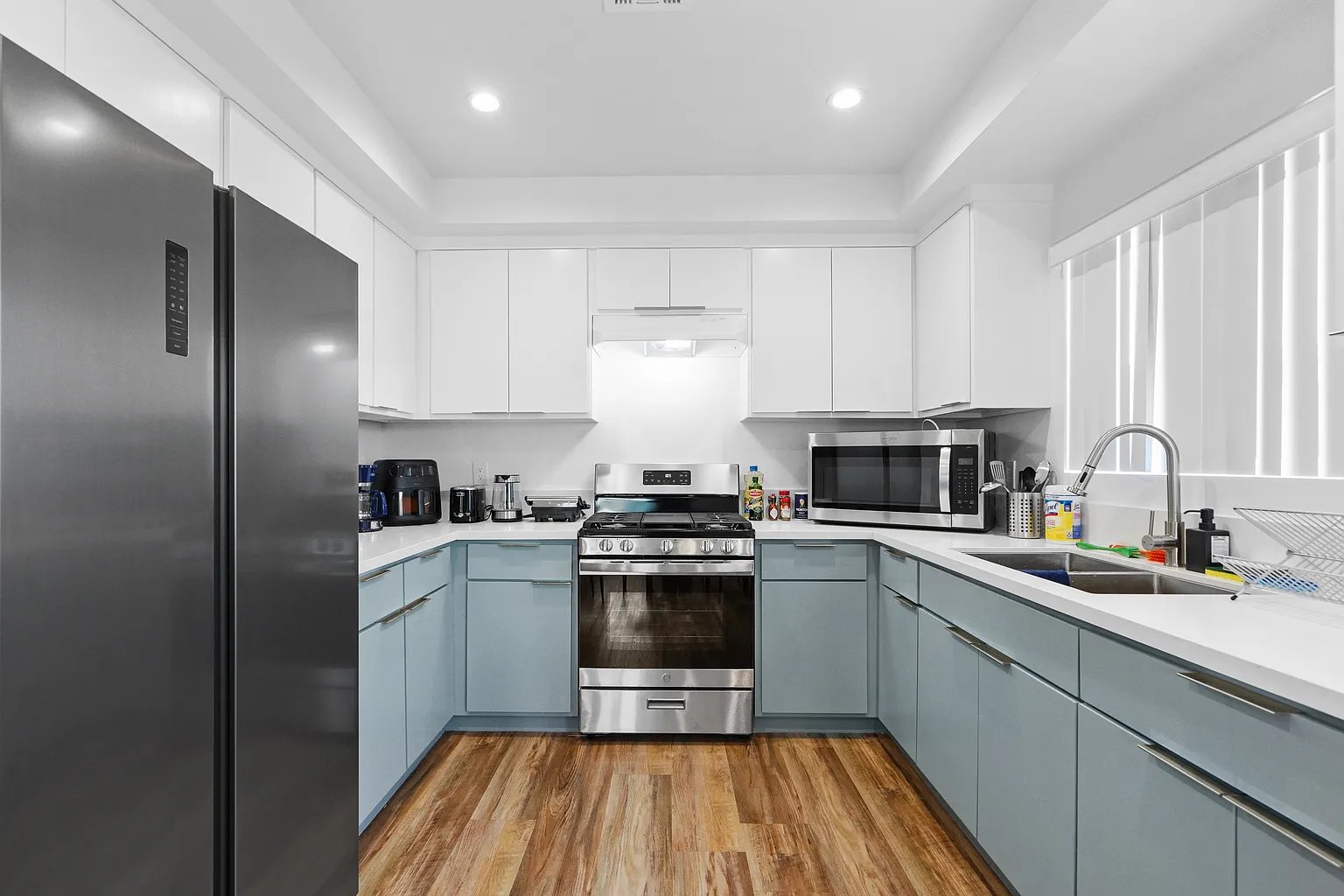 Culver City furnished apartment U-shaped kitchen with blue cabinets, quartz countertops, and gas range