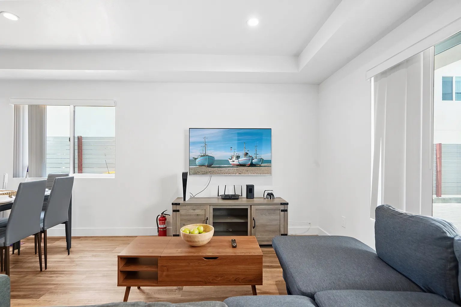 Culver City furnished apartment open-concept living room with sectional sofa, wall-mounted TV, and dining area
