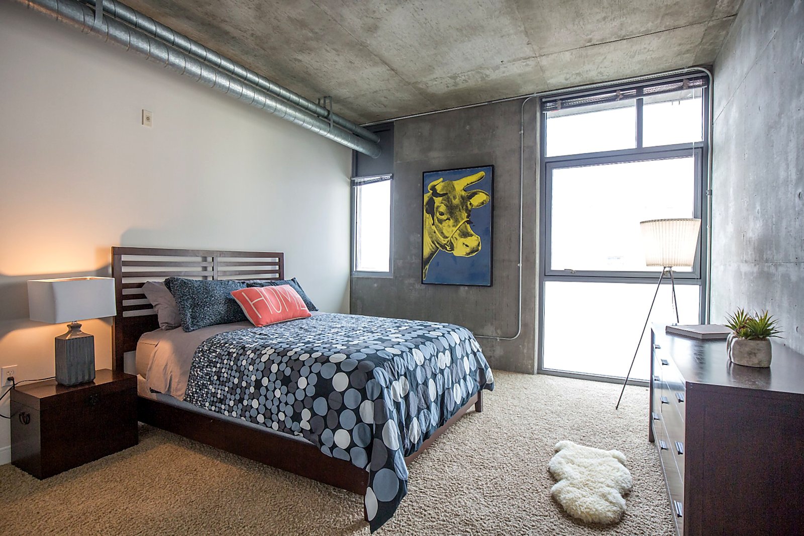 Downtown LA corporate housing bedroom with pop art, exposed ductwork, and natural light