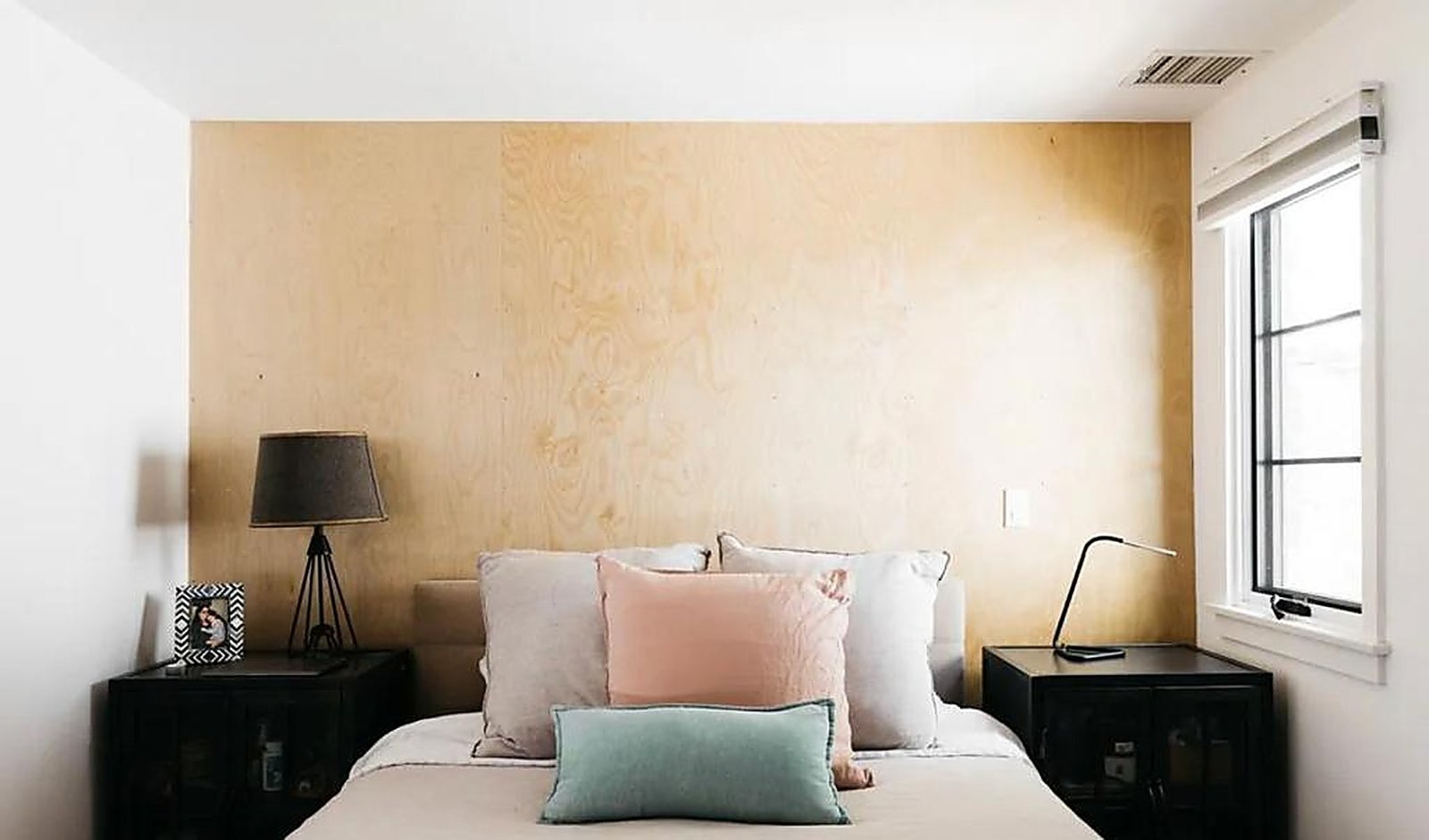 Cozy bedroom with plywood accent wall and colorful pillows in Santa Monica rental
